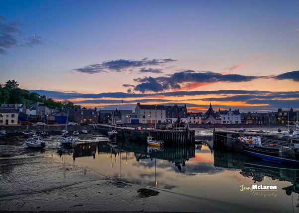 Final hours of sun reflecting the houses and boats in stonehaven harbour